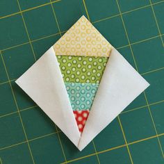 an origami piece is sitting on top of a green cutting board with white fabric