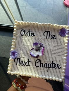 a decorated sign that says onto the next charter with flowers on it and pearls around the edges