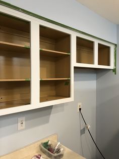 an empty kitchen with white cabinets and green trim on the wall above it is being painted