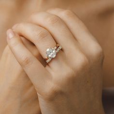 a woman's hand holding an engagement ring with two stones on it and the other side