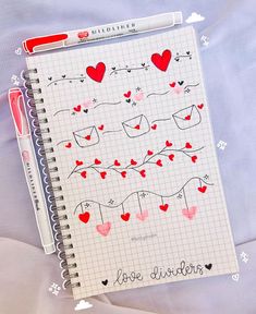 a notepad with hearts on it next to a pen