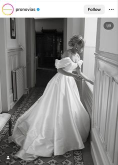 a woman in a wedding dress leaning against a wall with her hand on the door