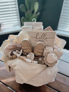 a basket filled with lots of baby items on top of a wooden table next to a window