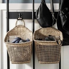 two wicker baskets are hanging on the wall next to a coat rack and purse