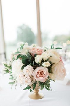 a vase filled with pink and white flowers on top of a table next to a window