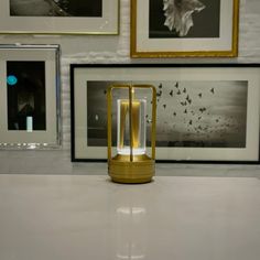 a lamp sitting on top of a white counter next to pictures and framed photos behind it