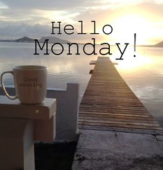 a coffee cup sitting on top of a wooden dock next to the ocean with words hello monday