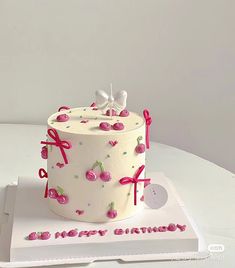 a white cake with cherries and bows on it