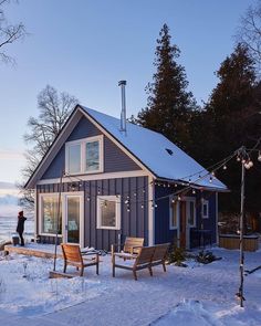 a small blue cabin in the snow with string lights