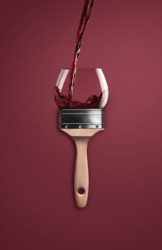 a red wine being poured into a glass with a wooden spatula attached to it