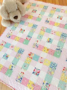 a teddy bear sitting on top of a pink quilt