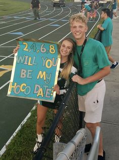 two people standing next to each other holding a sign