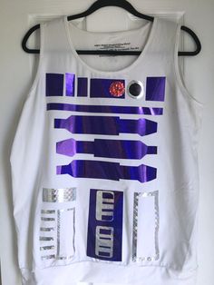 a white tank top with purple and silver designs on the front, hanging from a hanger