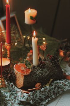 a table topped with candles and fruit on top of a cloth covered table next to other decorations