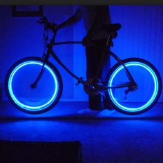 a person standing next to a bike with blue lights on it's rims