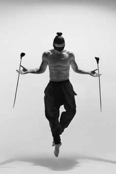 a man with two poles in his hands and no shirt on, jumping through the air