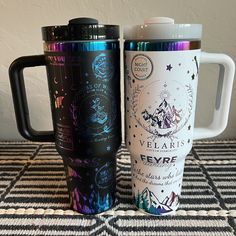 two travel mugs sitting next to each other on a table