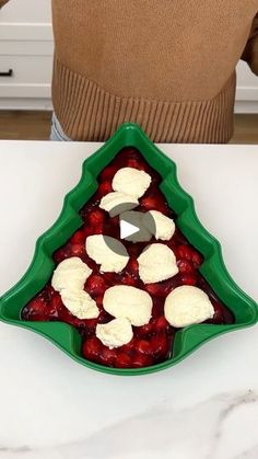 a person standing in front of a christmas tree shaped dessert