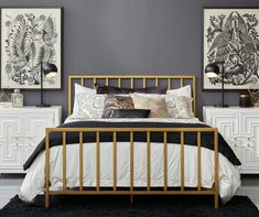 a bed with white sheets and black pillows in a room next to two framed pictures on the wall