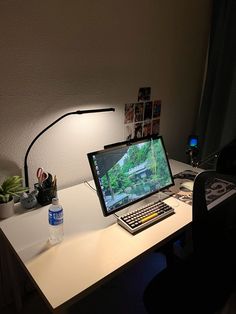 a laptop computer sitting on top of a white desk next to a bottle of water