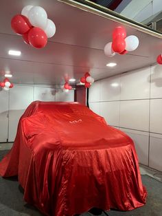 a car covered in a red cloth with balloons