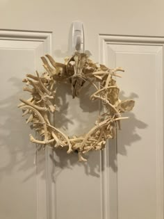 a wreath made out of driftwood hangs on a door handle in front of a white door