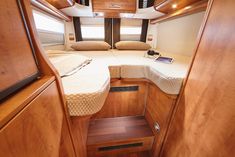 the inside of a motor home with wood paneling and white bedspreads