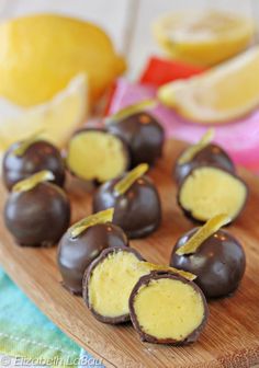 chocolate covered candies are sitting on a cutting board with lemons in the background