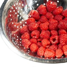 fresh raspberries in a colander with water droplets on the bottom and inside