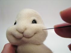 a stuffed animal is being needle - fed by someone's hand with a needle