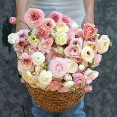 a person holding a basket filled with pink and white flowers