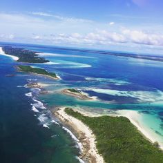 an aerial view of the ocean and landforms in the tropical island area, with blue water