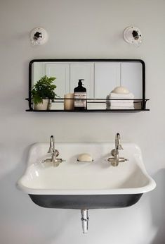 a bathroom sink sitting under a mirror next to a shelf filled with bottles and soaps