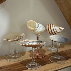 three wine glasses sitting on top of a wooden table next to seashells and oysters