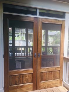 two wooden doors with glass panels on the outside of a home's front porch