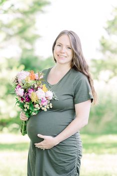 a pregnant woman holding a bouquet of flowers in her hands and smiling at the camera