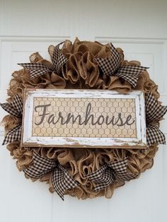 a wreath with the word farmhouse hanging on it's front door, decorated with burlap