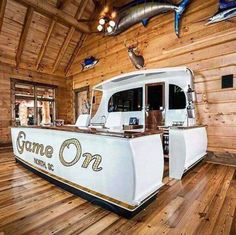 a large white boat sitting on top of a wooden floor next to a wall covered in wood