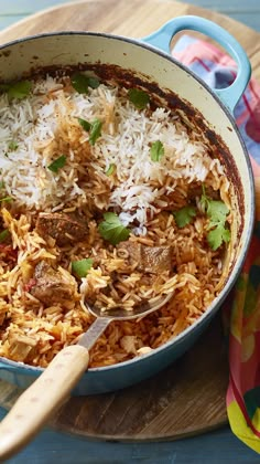 a pot filled with rice and meat on top of a wooden cutting board