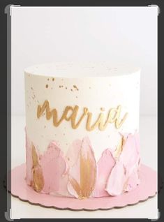 a white and pink cake with gold lettering on top