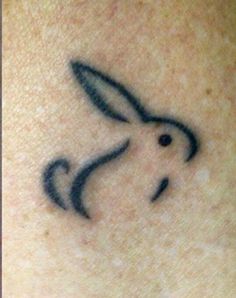 a small tattoo on the back of a woman's neck with a rabbit design