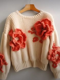 a white sweater with red flowers on it