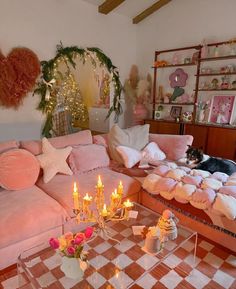 a living room filled with lots of pink furniture and candles on top of the coffee table