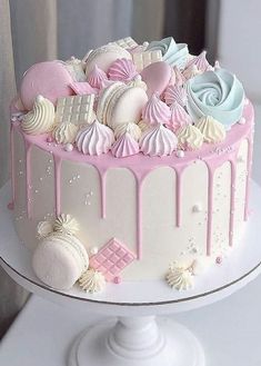 a white cake with pink icing and seashells on the top is sitting on a pedestal