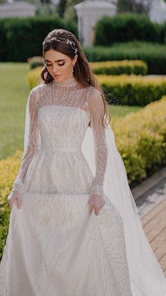 a woman in a white wedding dress and veil walking down the street with her hand on her hip