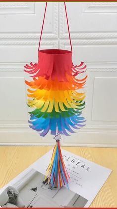 a multicolored paper bird hanging from a string with the words, follow for more like & save