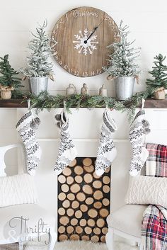 a living room decorated for christmas with stockings on the mantel and trees in pots