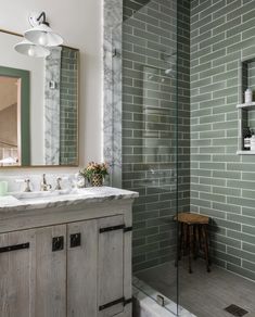 a bathroom with two sinks and a walk in shower next to a wooden cabinet under a mirror