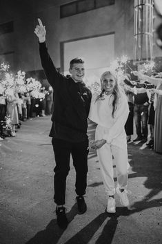 a man and woman standing next to each other with sparklers in the air behind them