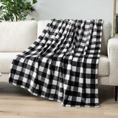 a black and white checkered blanket sitting on top of a couch next to a potted plant